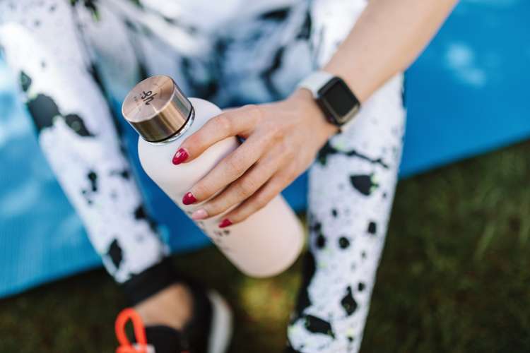 woman holding a metal water tumbler