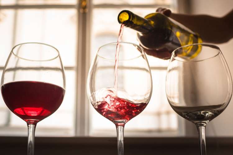 sommelier pouring wine into three glasses for a tasting