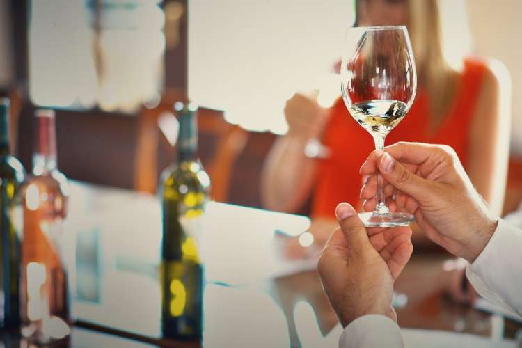 wine taster holding up a glass of wine to evaluate it