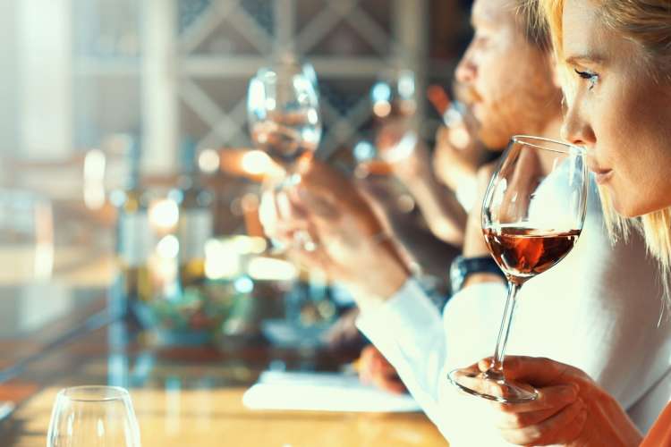 a group in a well-lit room tasting wines