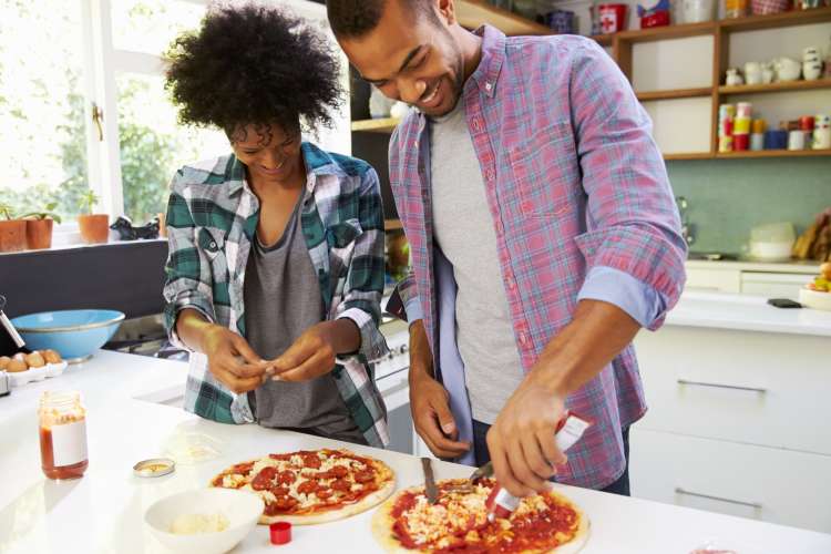 young couple making homemade pizza in their kitchen