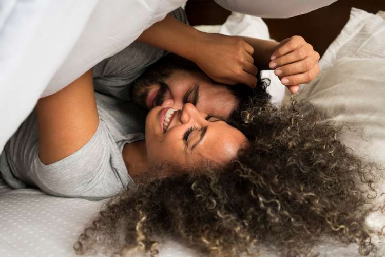 couple laughing in bed trying to stay up all night