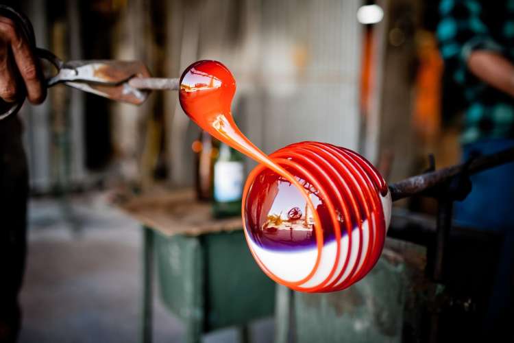 artist spinning hot glass on a rod 