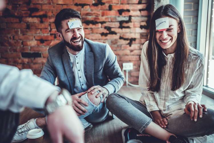 laughing people with clues on sticky notes stuck to their foreheads