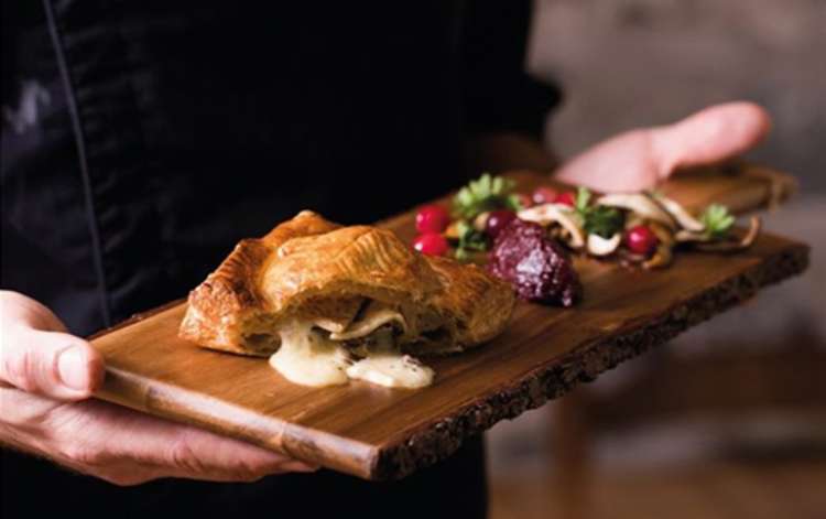 Hands holding a small wooden board of food from The Lapin Sauté in Quebec City