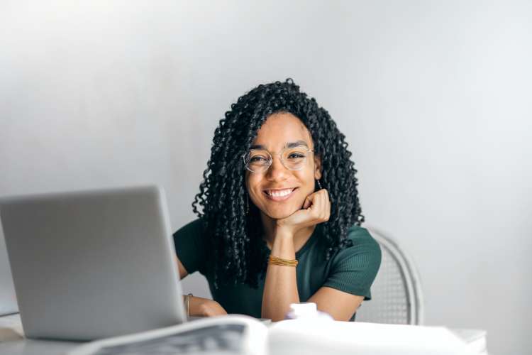 young woman smiling with laptop while playing online games with her teammates