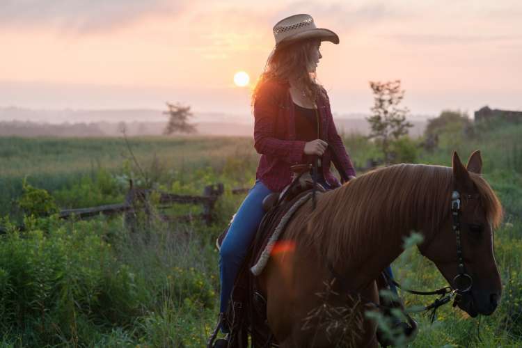 woman horseback riding at sunset