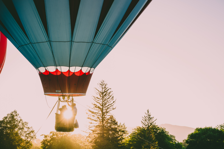 a hot air balloon lifting off at sunset