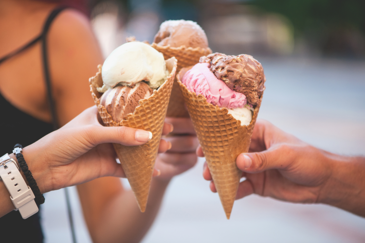 Three hands holding ice cream cones
