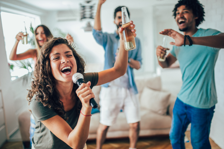 group of young friends singing karaoke at home