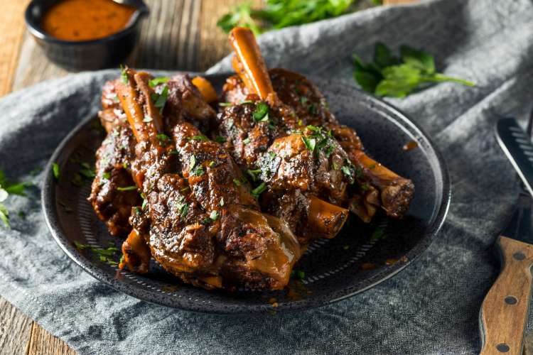 roasted lamb shank in a bowl with parsley garnish