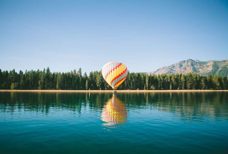 hot air balloon preparing to take flight over a lake