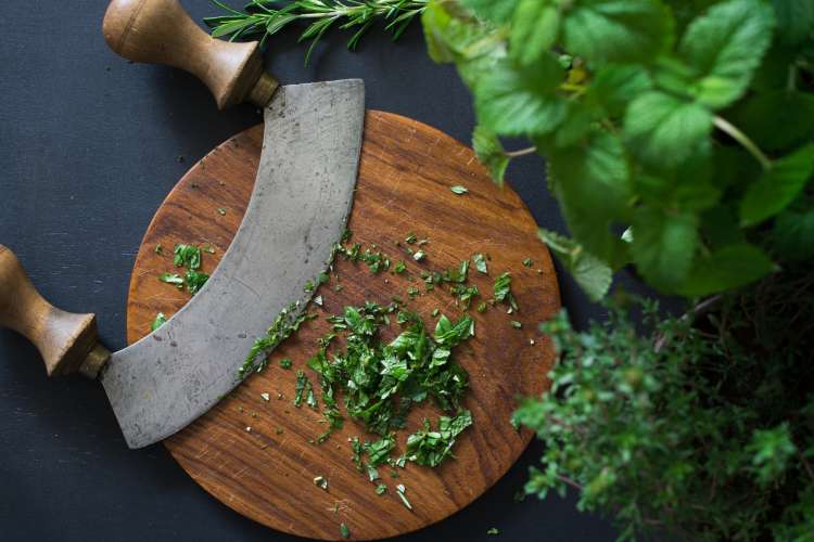 mezzaluna knife on a cutting board with herbs