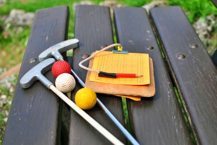 mini golf clubs, balls and score card on a table