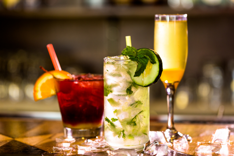 trio of colorful cocktails on a bar top