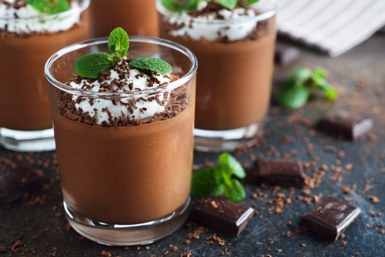 Chocolate mousse in a clear glass next to blocks of chocolate