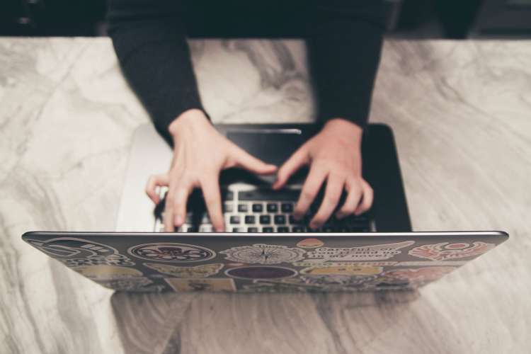 hands typing on a laptop keyboard during a virtual team meeting