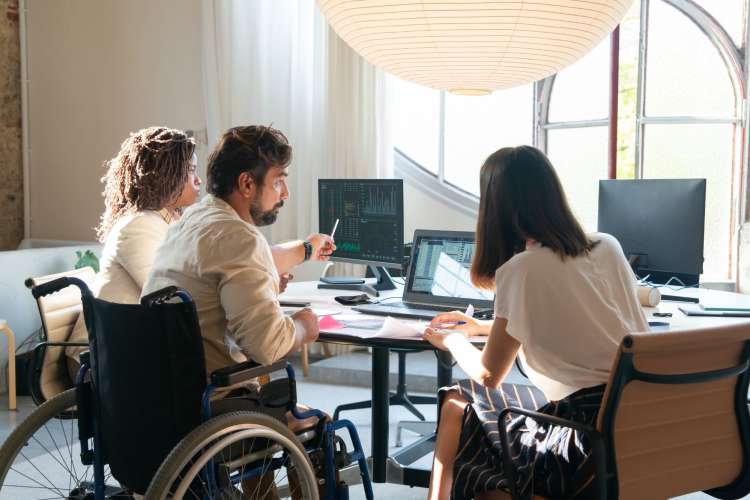 three employees work together on a project at a desk