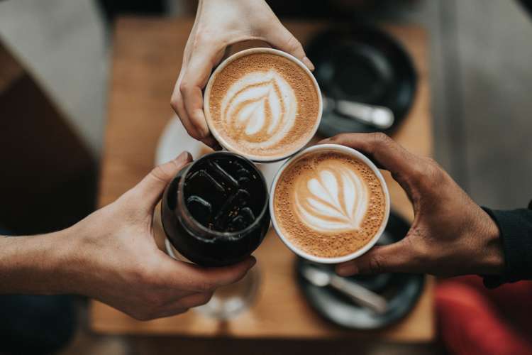 friends toasting mugs filled with lattes and iced coffee