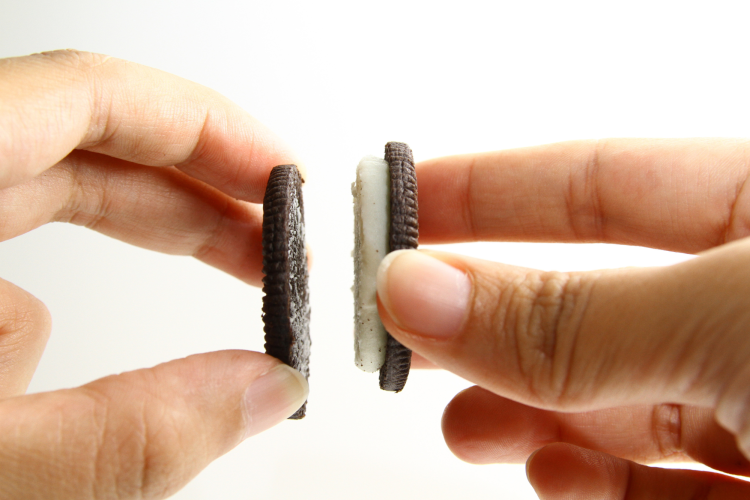 person splitting oreo in half