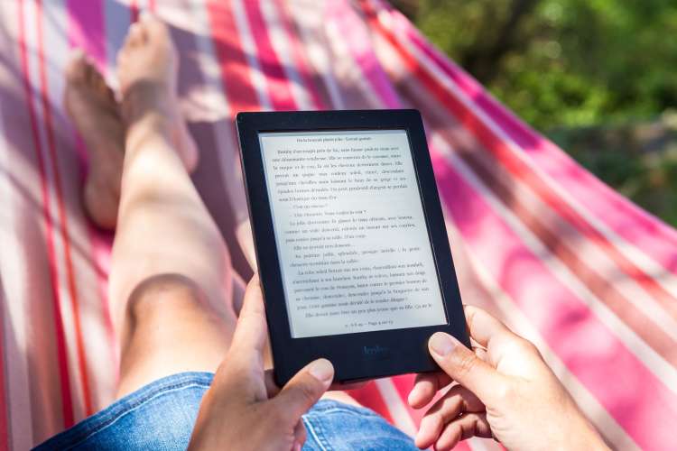 woman reading a kindle paperwhite on a hammock