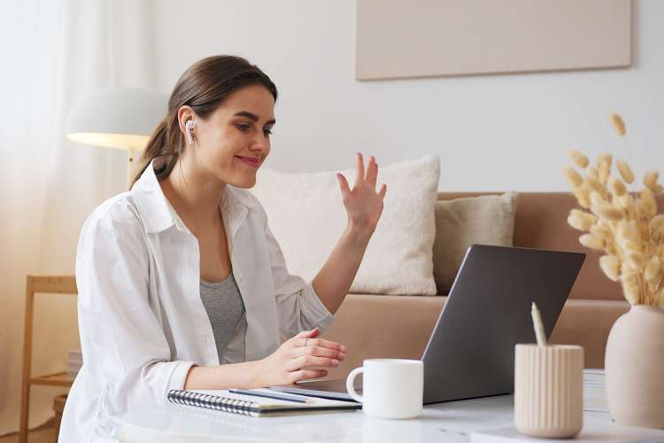 woman waving to coworkers on zoom during a happy hour