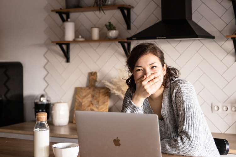 woman laughing with hand over her mouth while playing online games with her remote team