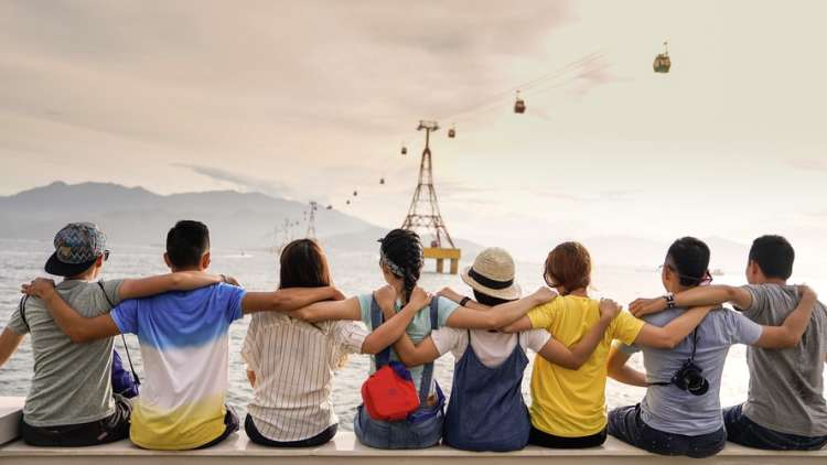 A team sits with their arms around each others shoulders after a day of team building activities