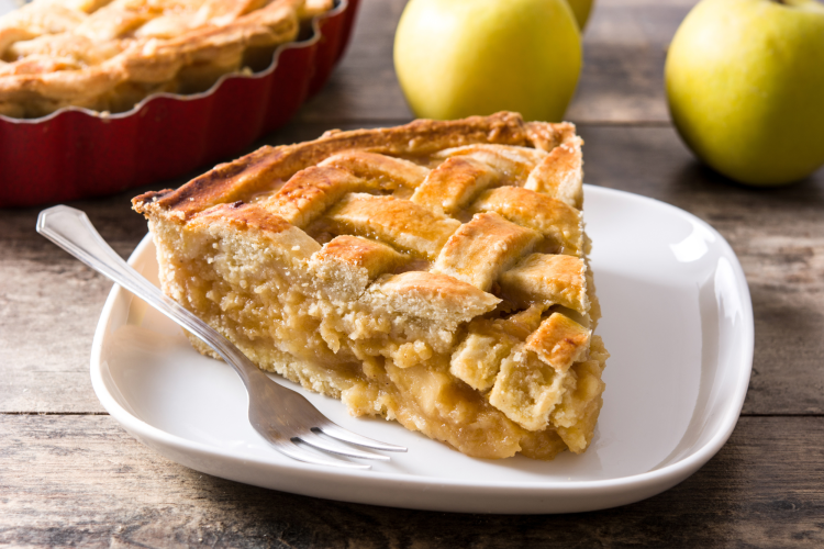 A slice of apple pie, a popular dessert, on a white plate