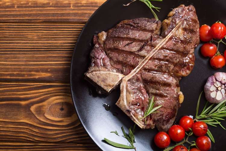 porterhouse steak sliced on a plate with roasted cherry tomatoes