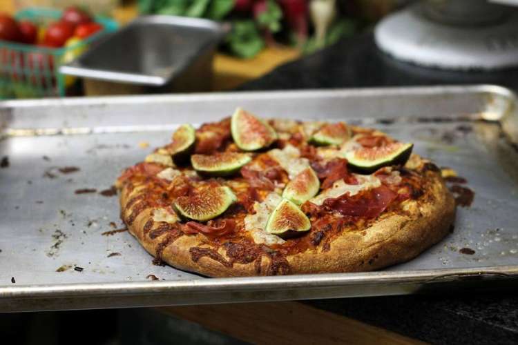 pizza topped with figs on a baking sheet