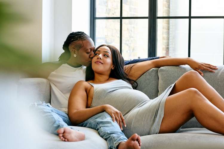 a couple expecting a baby having quiet time on the sofa