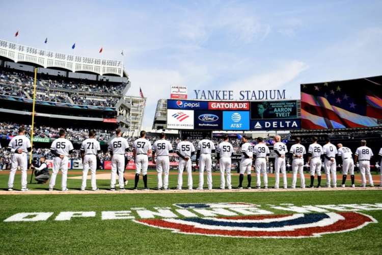 yankees baseball players standing shoulder to shoulder on the field in yankee stadium