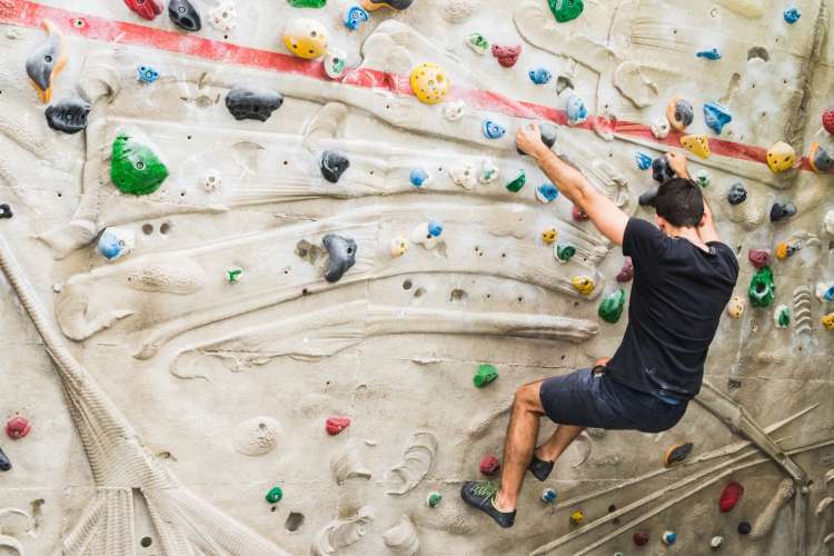 man climbing a rock wall at a gym