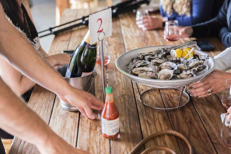 people enjoying a tray of raw oysters with lemon on a food tour