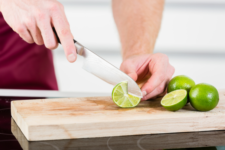 chef using a santoku knife to slice limes