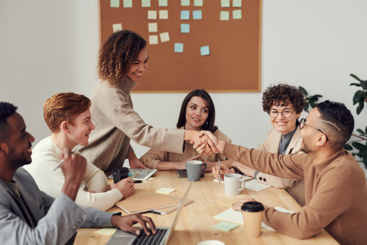 a group of professionals shake hands with a woman