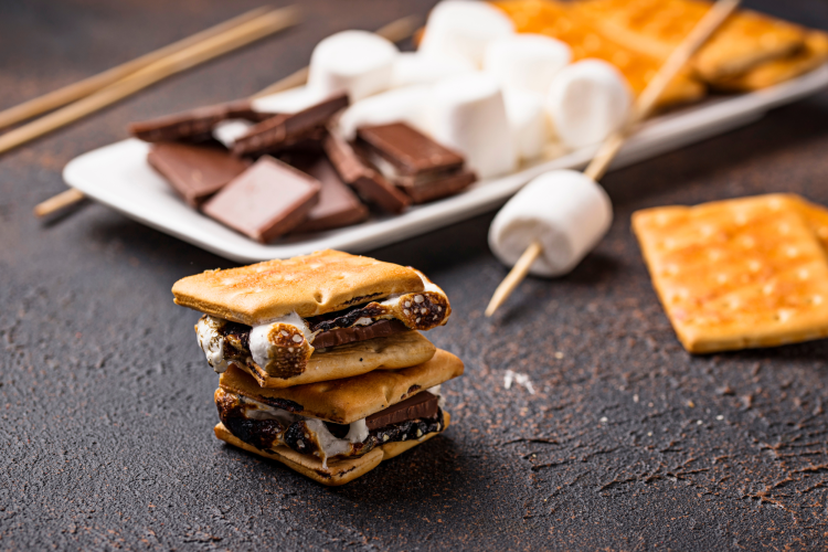 One s'more stacked on top of another one in front of ingredients to make s'mores 