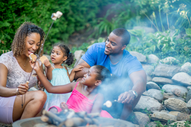 couple with kids enjoying a bonfire and s'mores