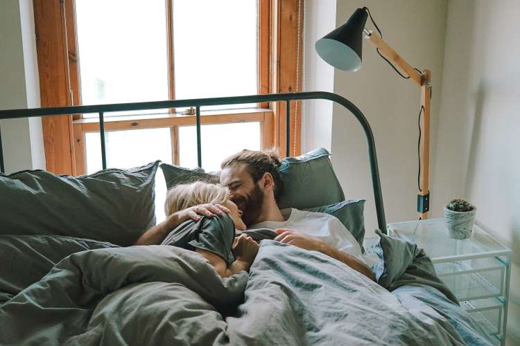 couple lying in bed with nice pillows and comfortable sheets