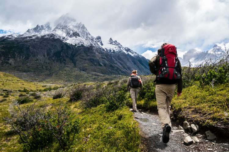 couple with hiking gear hiking toward the mountains