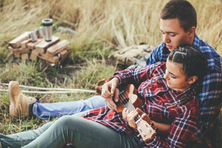 a couple playing the ukulele together outside