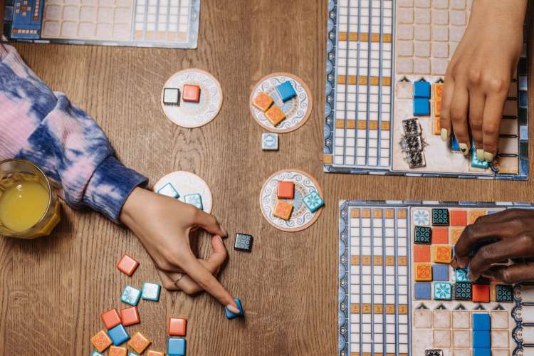 the hands of people playing a colorful board game