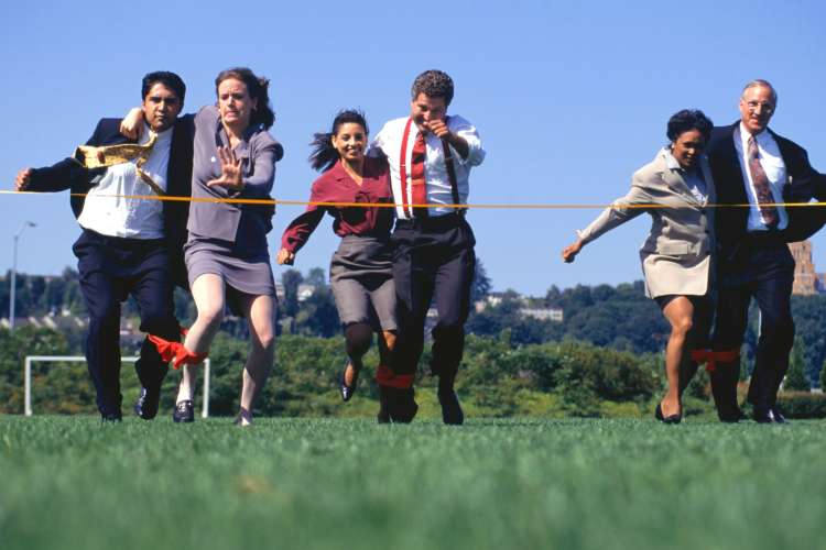 People in business attire running in a three-legged race