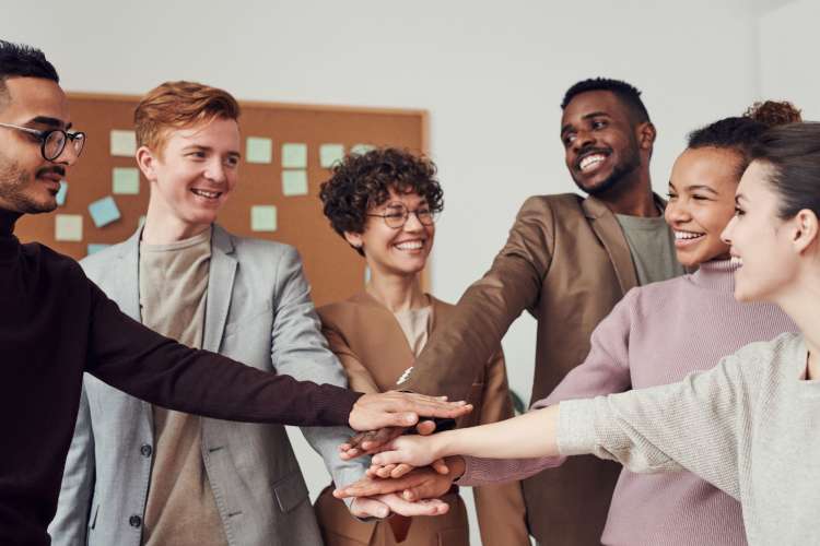 a group of young professionals celebrates a victory with an in-office high five