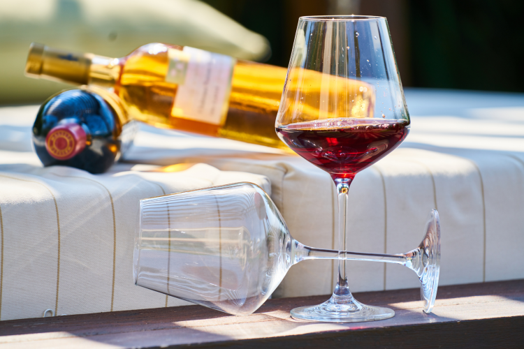 two wine glasses and two bottles of wine on a picnic table