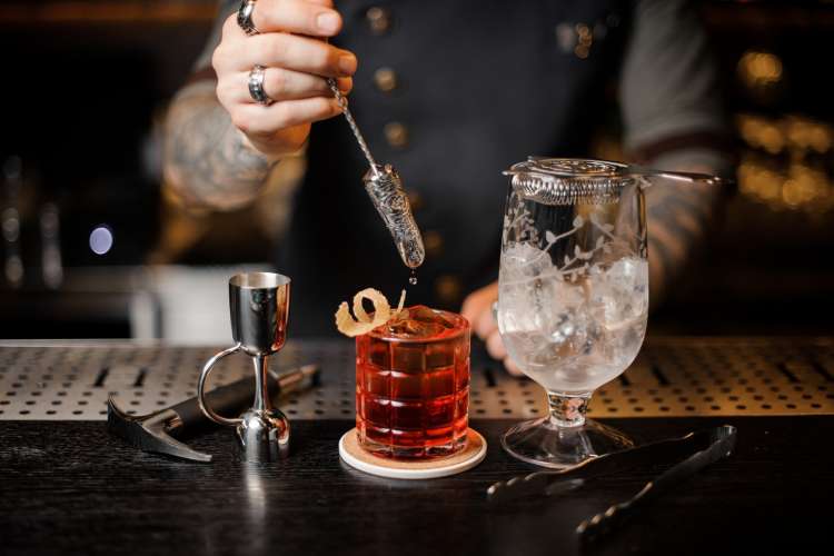 bartender pouring a whiskey cocktail