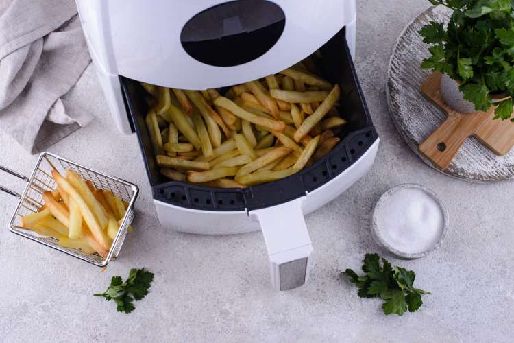 French fries being poured out of an air fryer basket