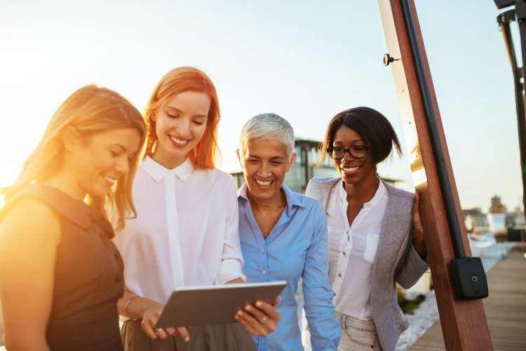 four diverse women chatting together outdoors in work clothes