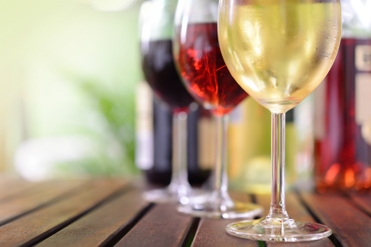 wine glasses lined up with red, white and rose wines